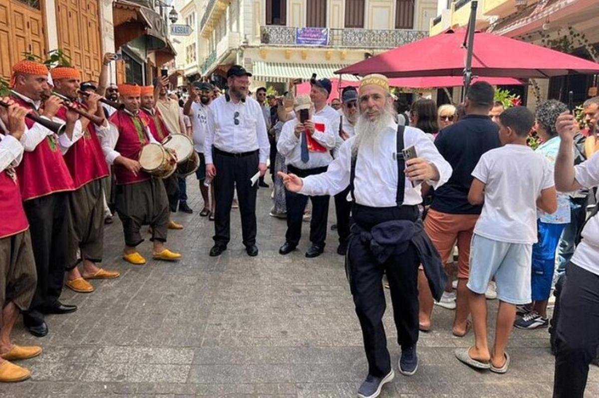 Un hombre con barba caminando entre una multitud de personas.