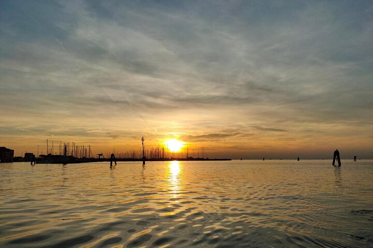 a group of people standing in the water at sunset