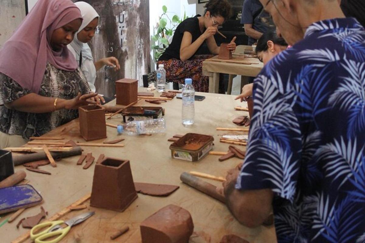 Un grupo de personas sentadas alrededor de una mesa haciendo cerámica.
