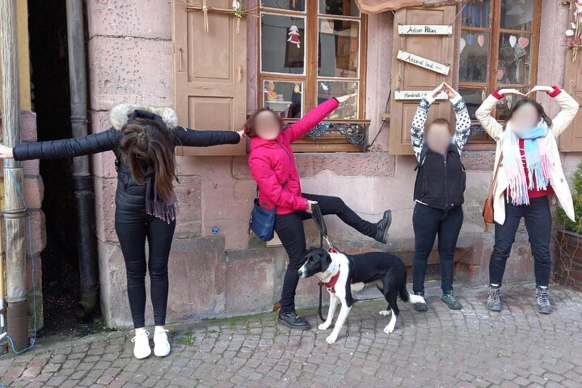 eine Gruppe von Mädchen steht mit einem Hund neben einem Gebäude