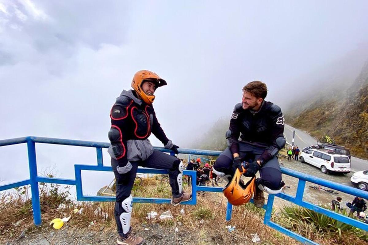 dua lelaki duduk di atas pagar di sisi gunung