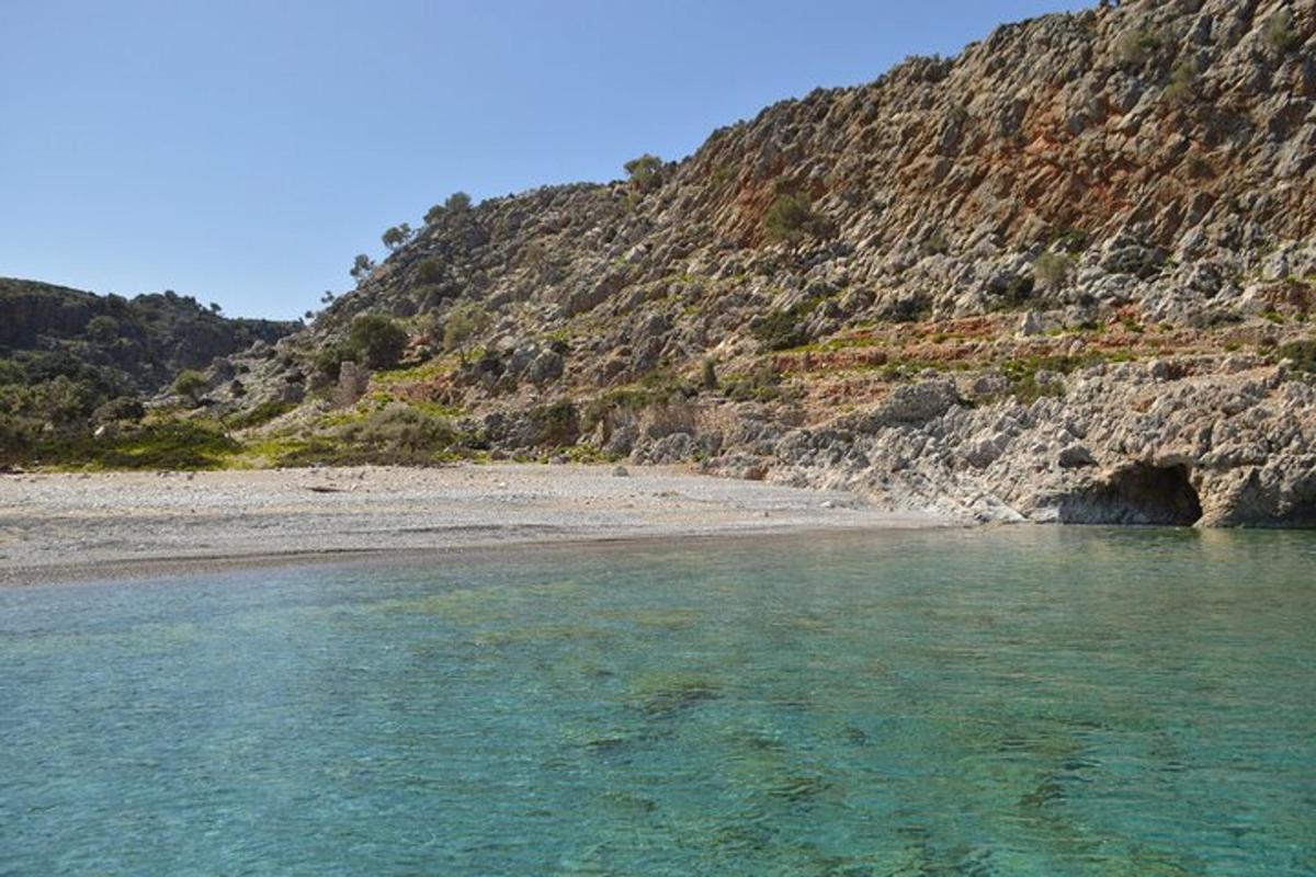 uma praia perto de uma montanha com água azul