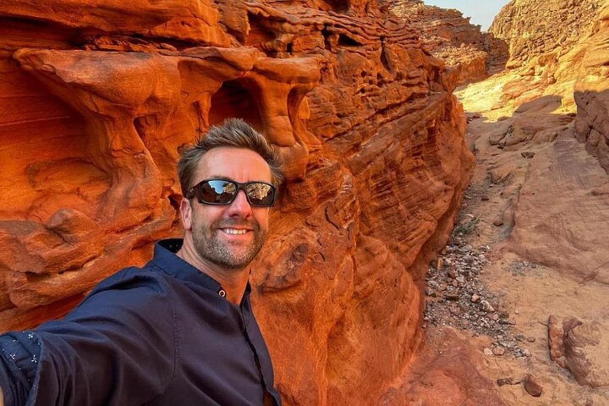 un uomo con occhiali da sole è in piedi in un canyon