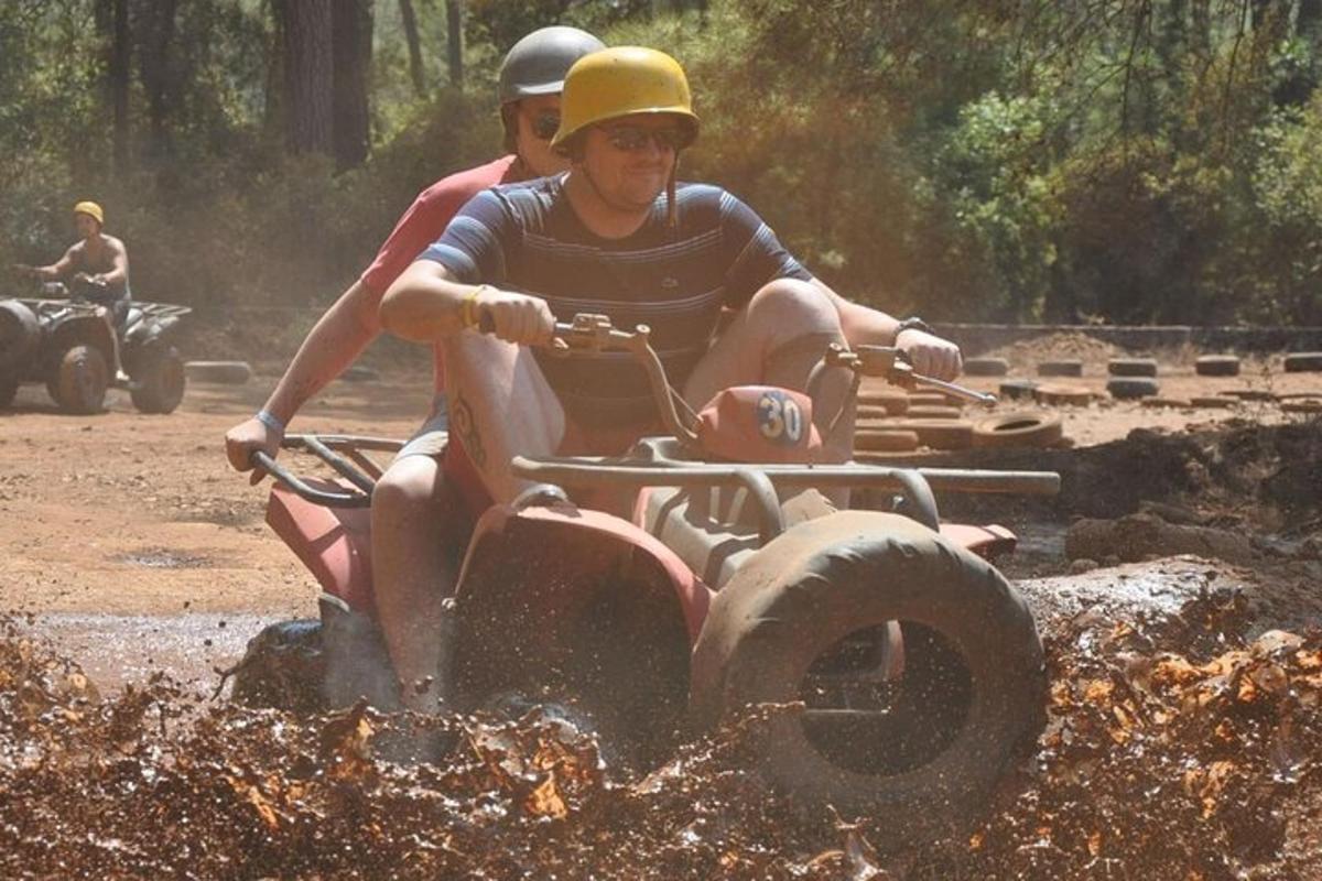 dva moška, ki se vozita na štirikolesniku skozi blato