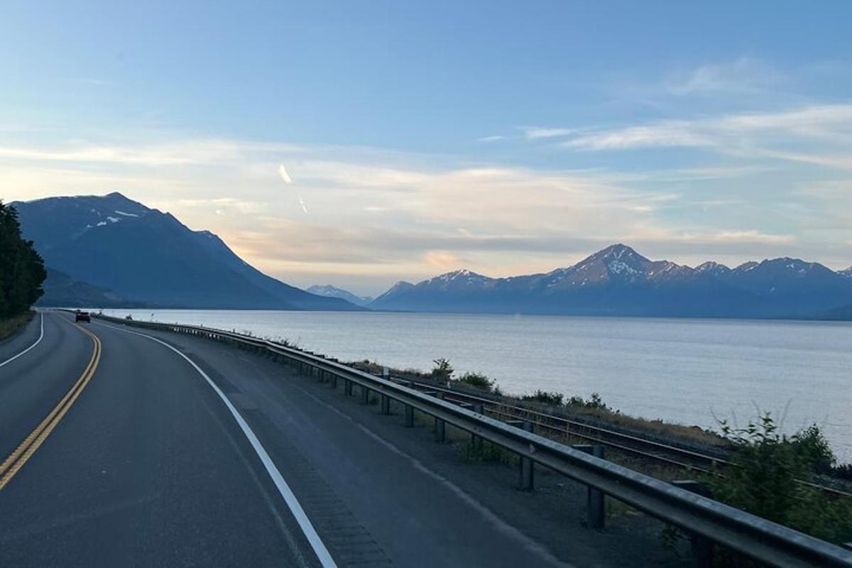 una carretera al costat d'una massa d'aigua amb muntanyes