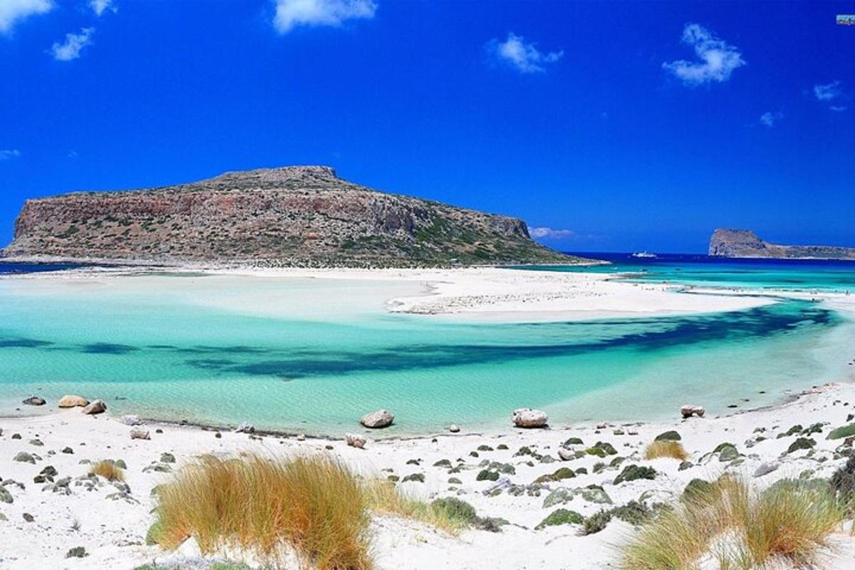 uma praia com água azul e uma montanha ao fundo