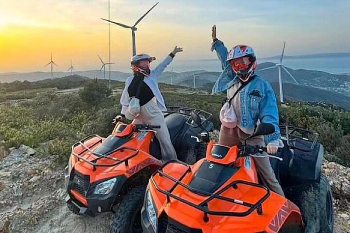 due persone su quad su una montagna con turbine eoliche