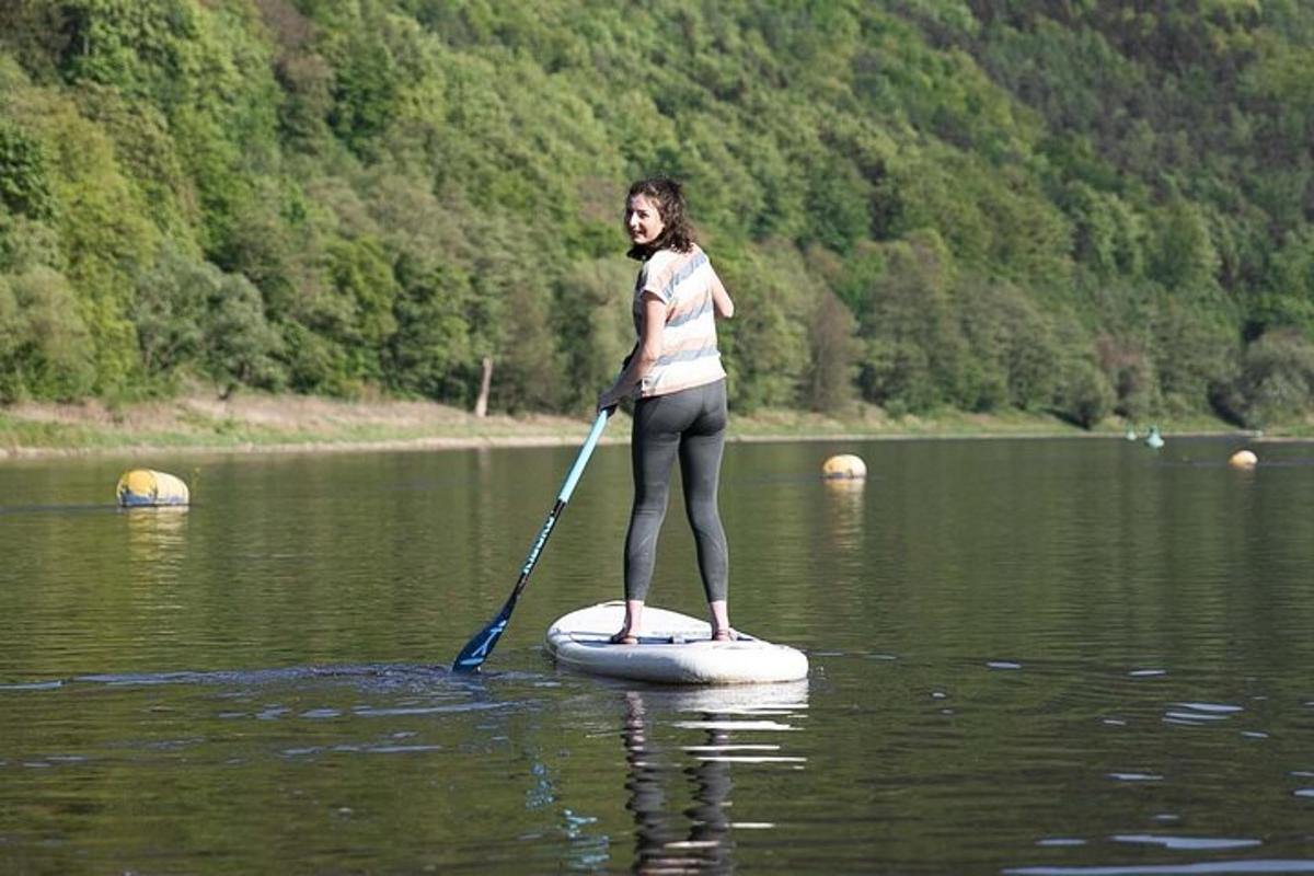 una dona dreta sobre una taula de paddle surf a l'aigua