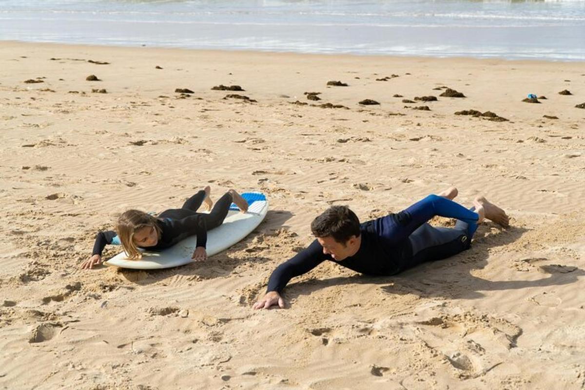 a man and a woman laying on a surfboard on the beach