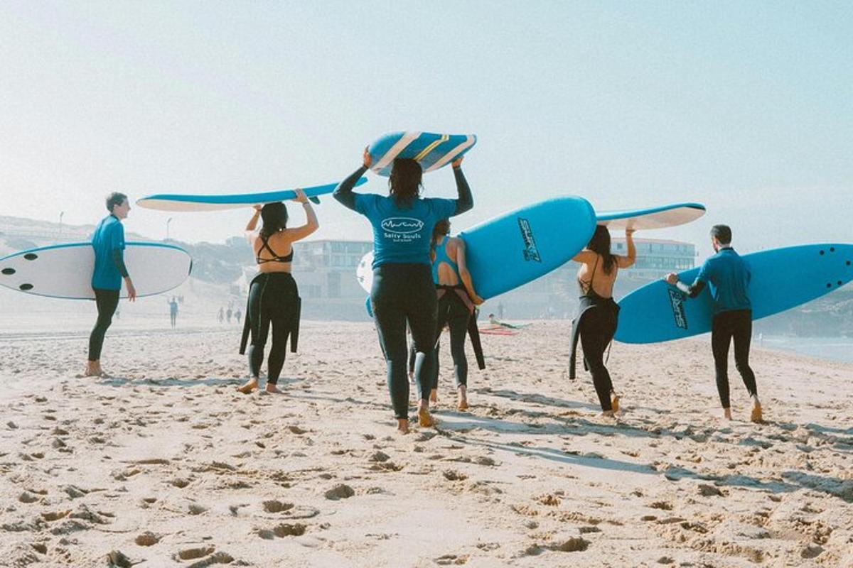 a group of people walking on the beach with surfboards