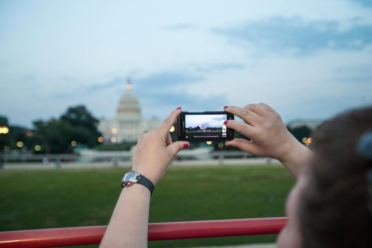 o femeie care fotografiază clădirea Capitoliului cu telefonul mobil