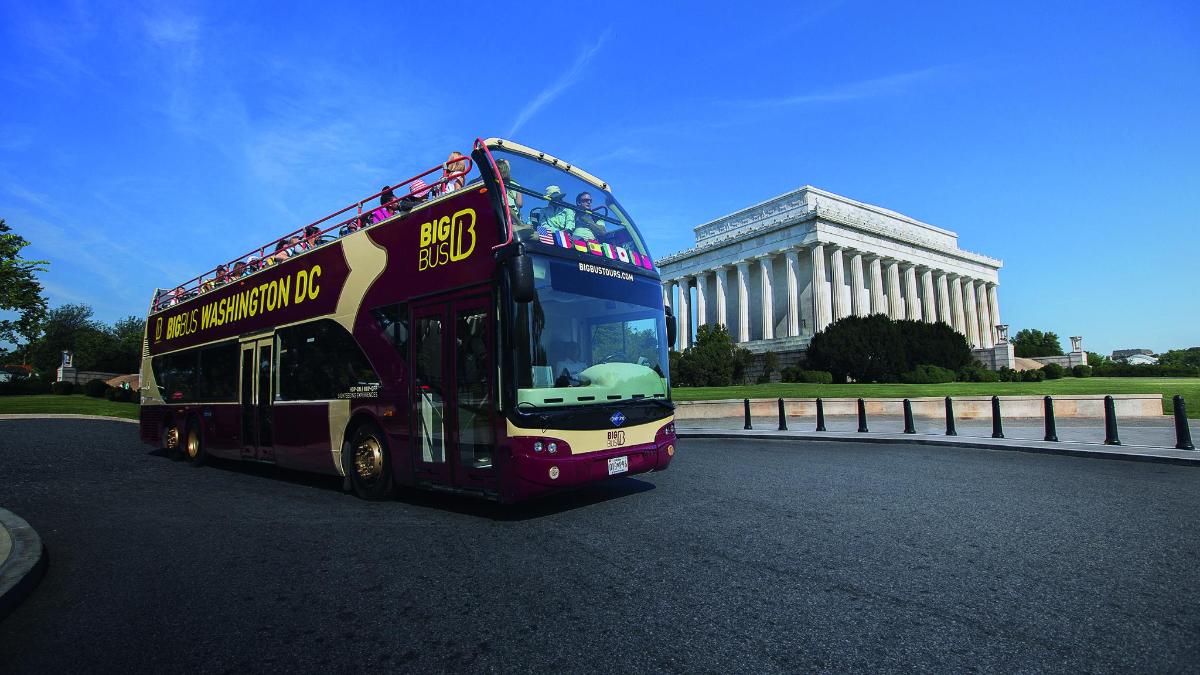 un autobuz cu etaj care trece pe lângă o clădire