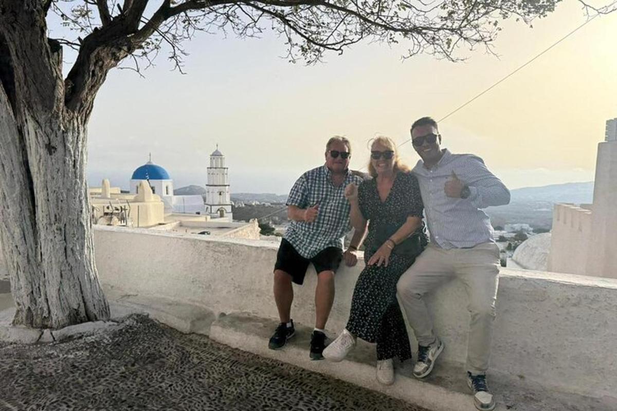 un grup de tres persones assegudes en una paret al costat d'un arbre