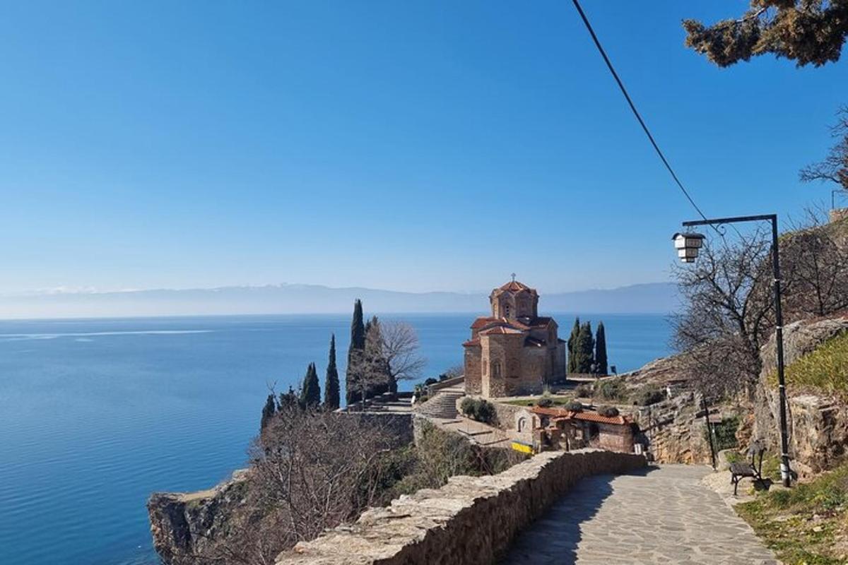a road leading up to a castle on a hill next to the ocean