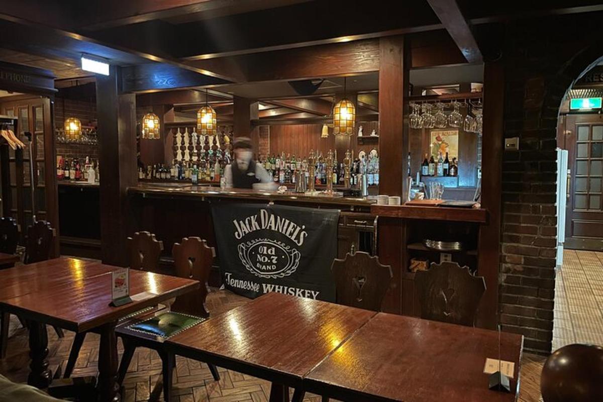 bar s dřevěnými stoly a mužem za barem