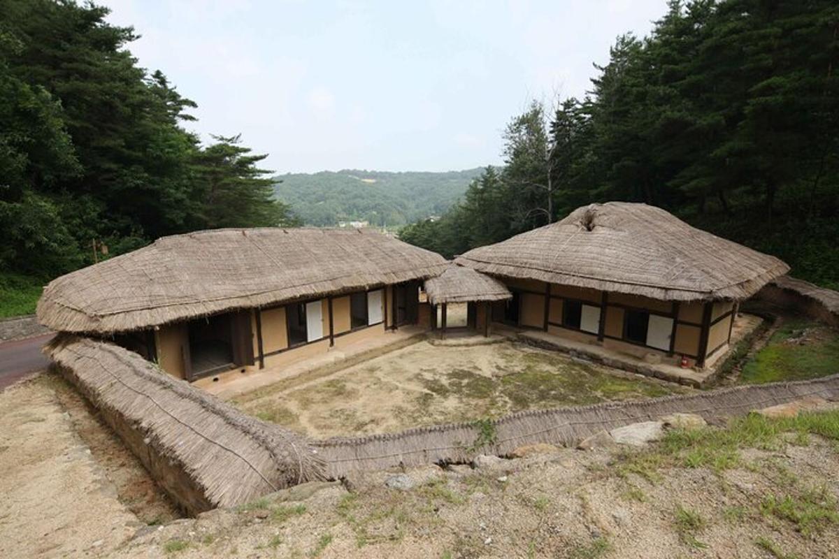 an old house with a straw roof on a hill