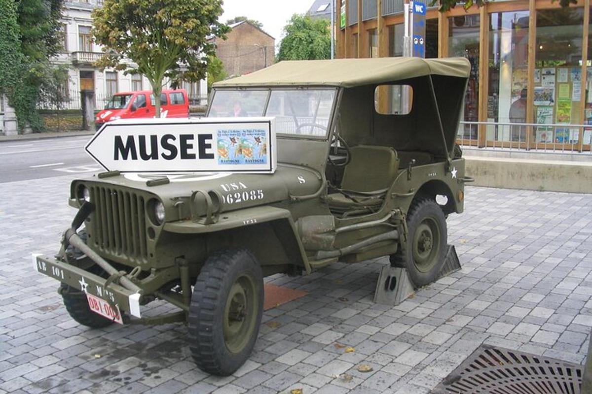 una jeep verde parcheggiata su una strada con un cartello