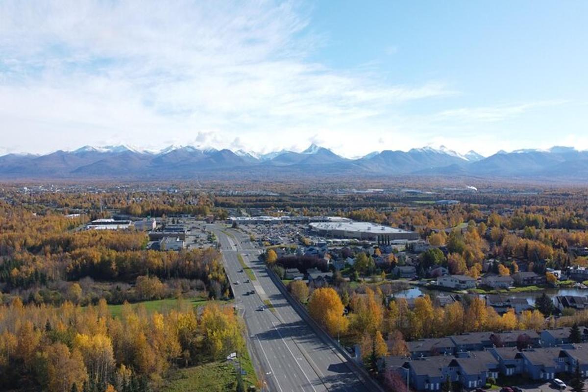 an aerial view of a city with mountains and a road