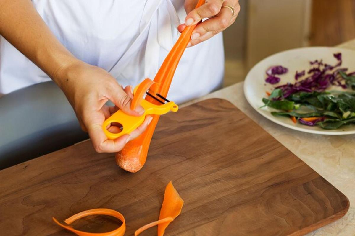 một người đang cầm một củ cà rốt trên thớt
