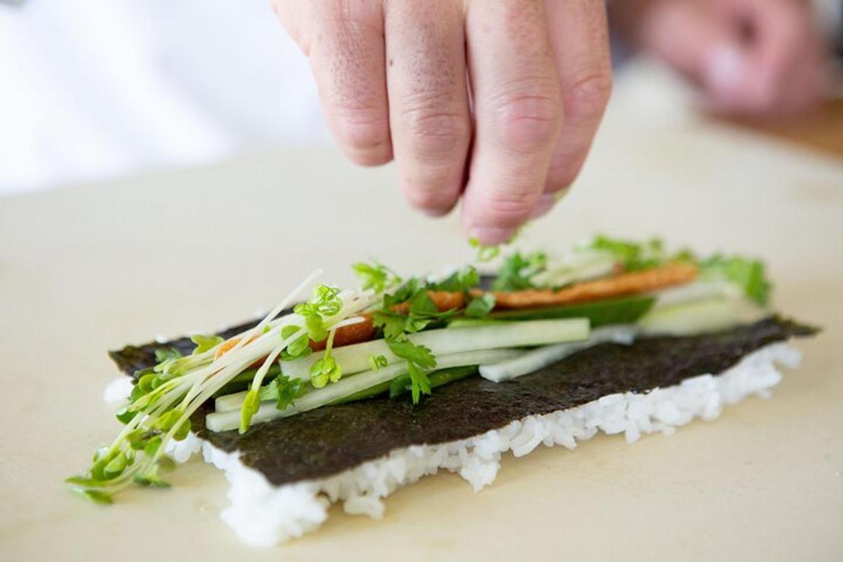 một người rắc rau lên trên một chiếc bánh sandwich