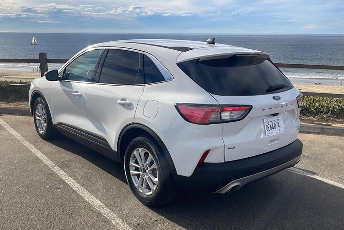 Un coche blanco estacionado en un estacionamiento cerca del océano.