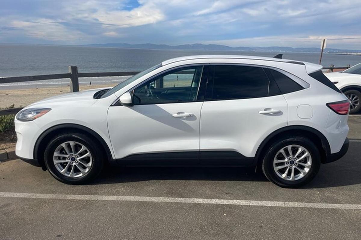 bílé auto zaparkované na parkovišti poblíž oceánu
