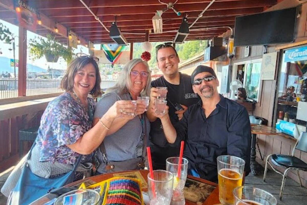 a group of people sitting at a table holding up glasses