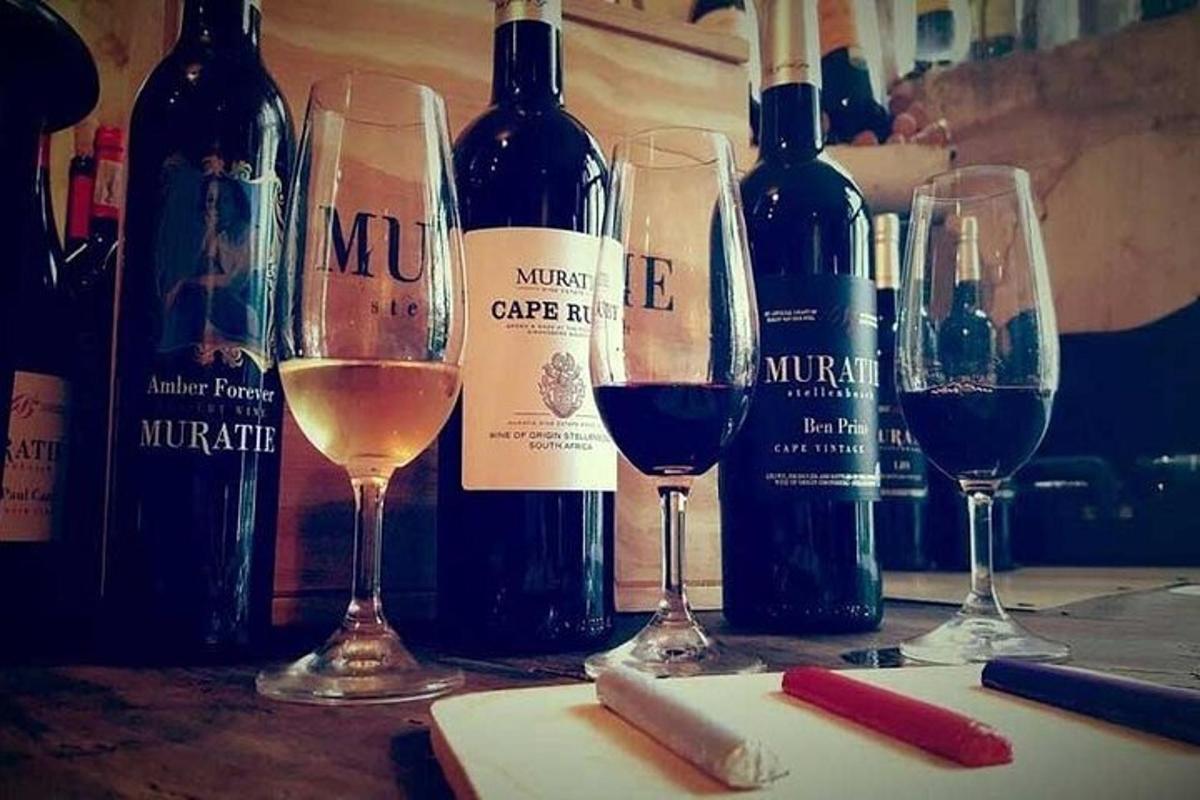 tri čaše vina i boce vina na stolu