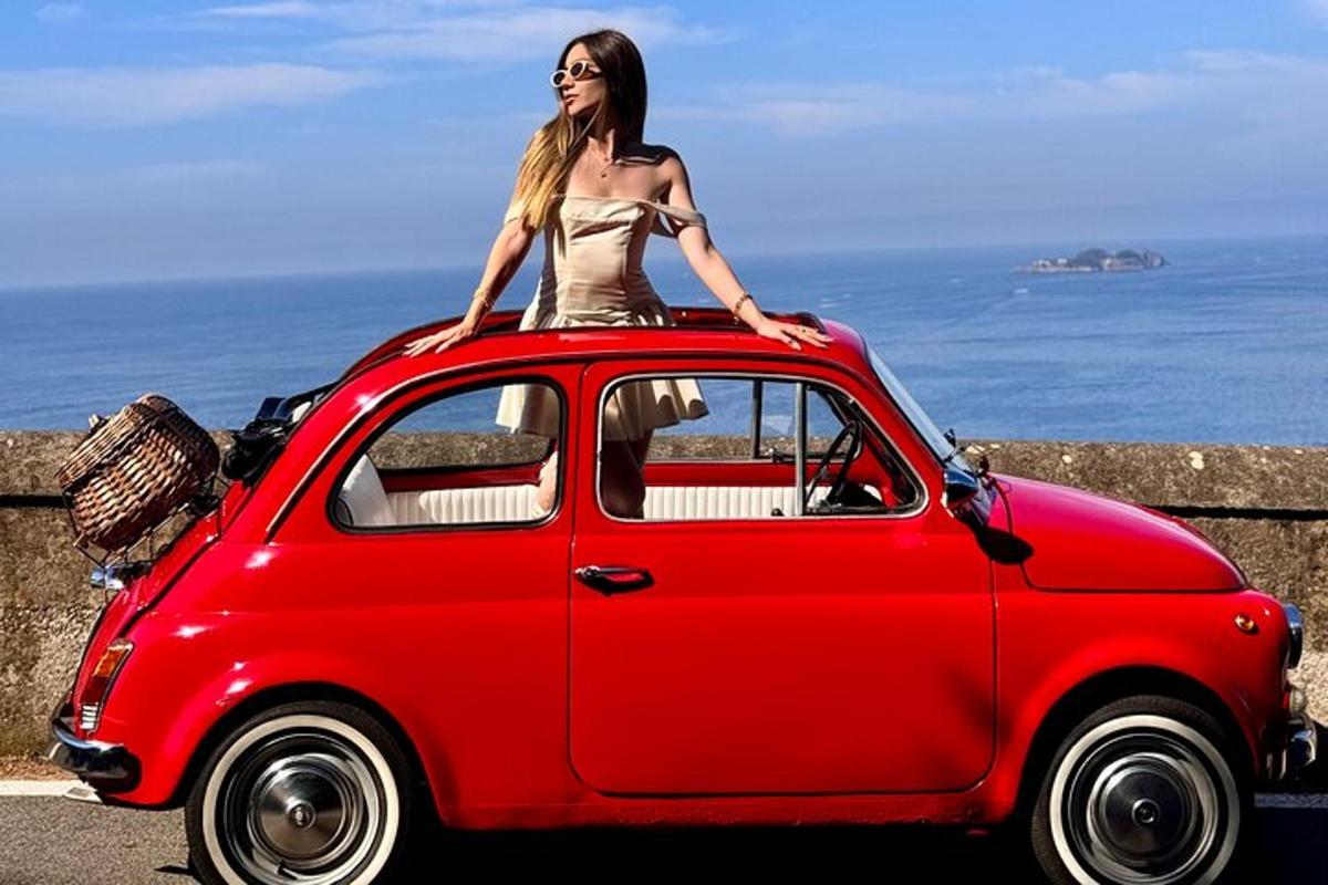 uma mulher sentada em cima de um carro vermelho