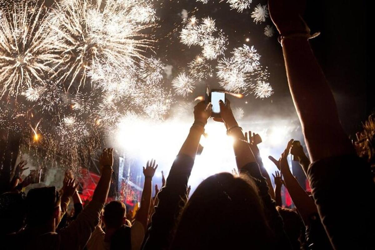 una multitud de persones en un concert fent fotos de focs artificials