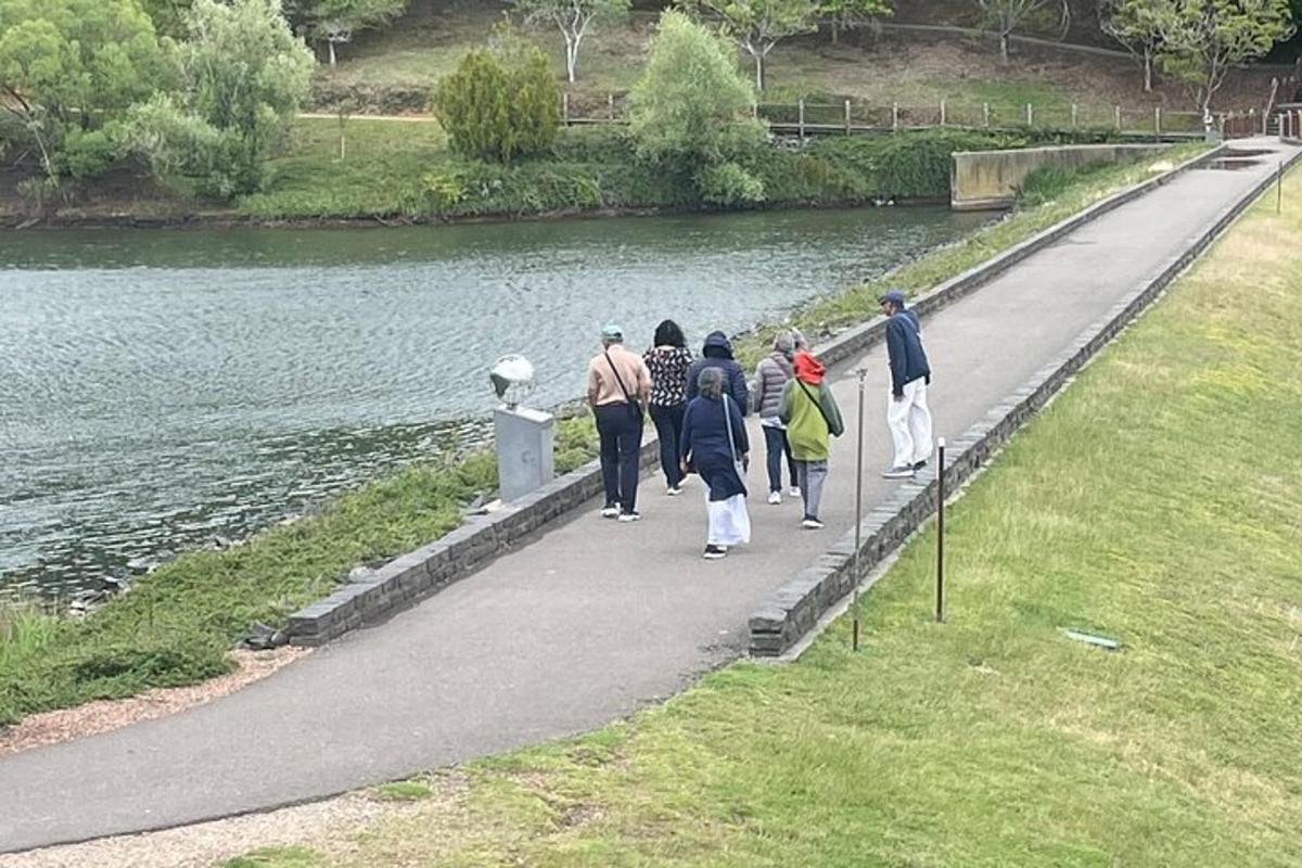 a group of people walking along a path next to a river