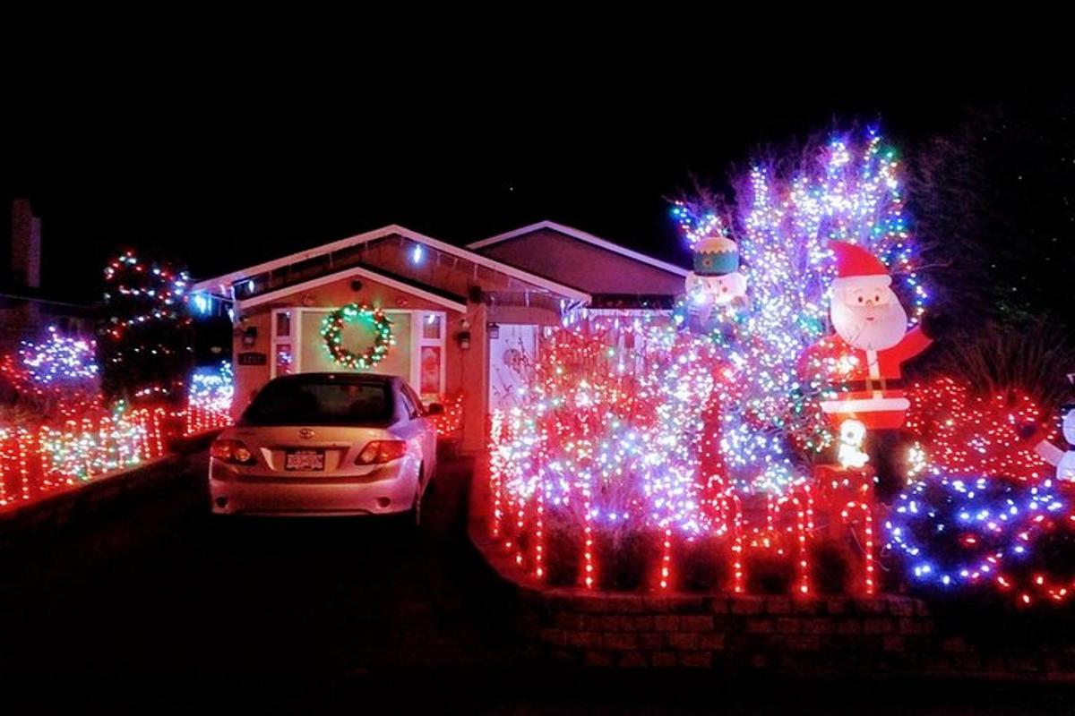una casa coperta di luci di Natale con un'auto davanti