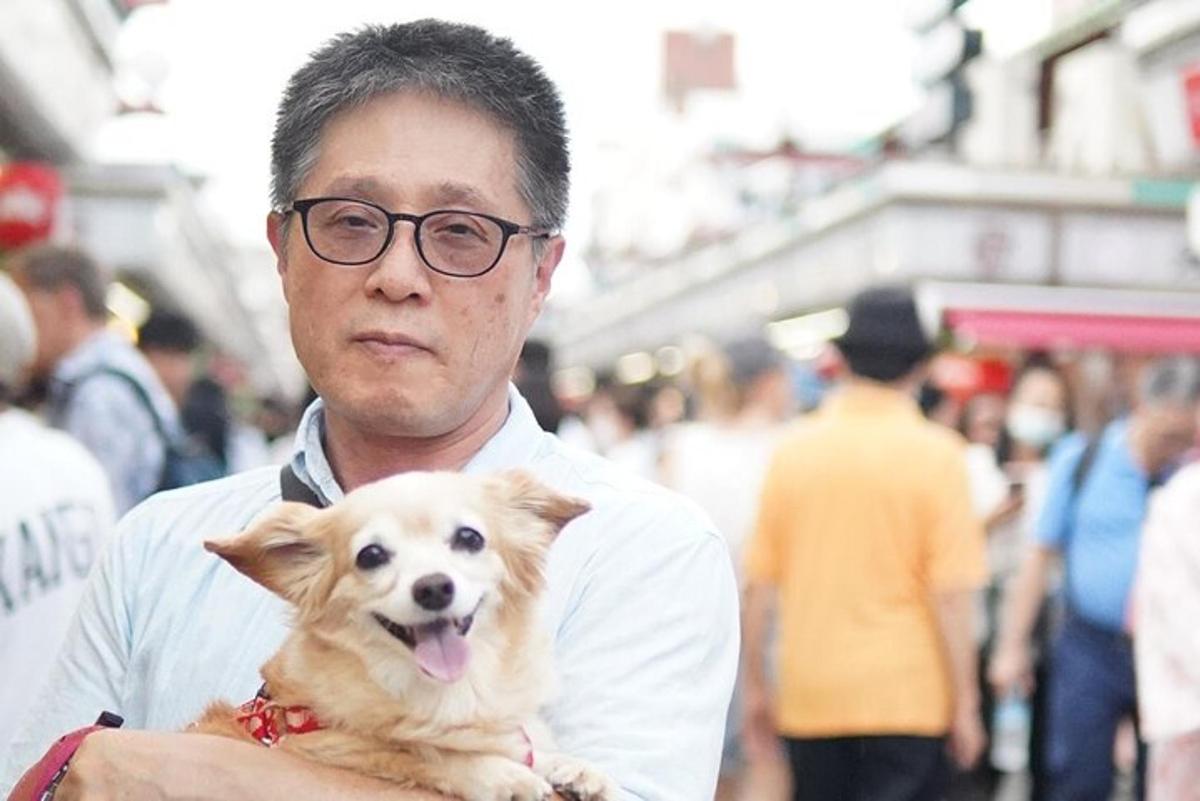 seorang lelaki memegang anjing kecil di tangannya
