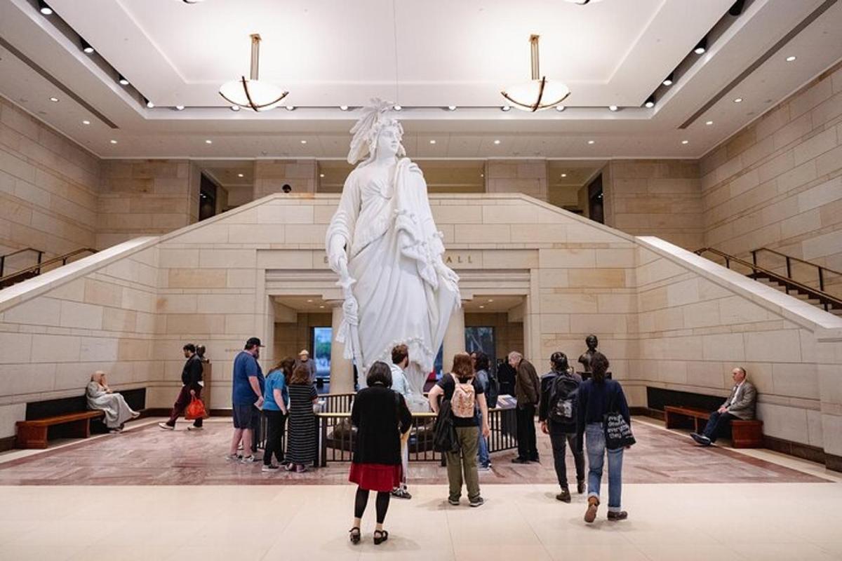 a group of people standing in a lobby looking at a statue