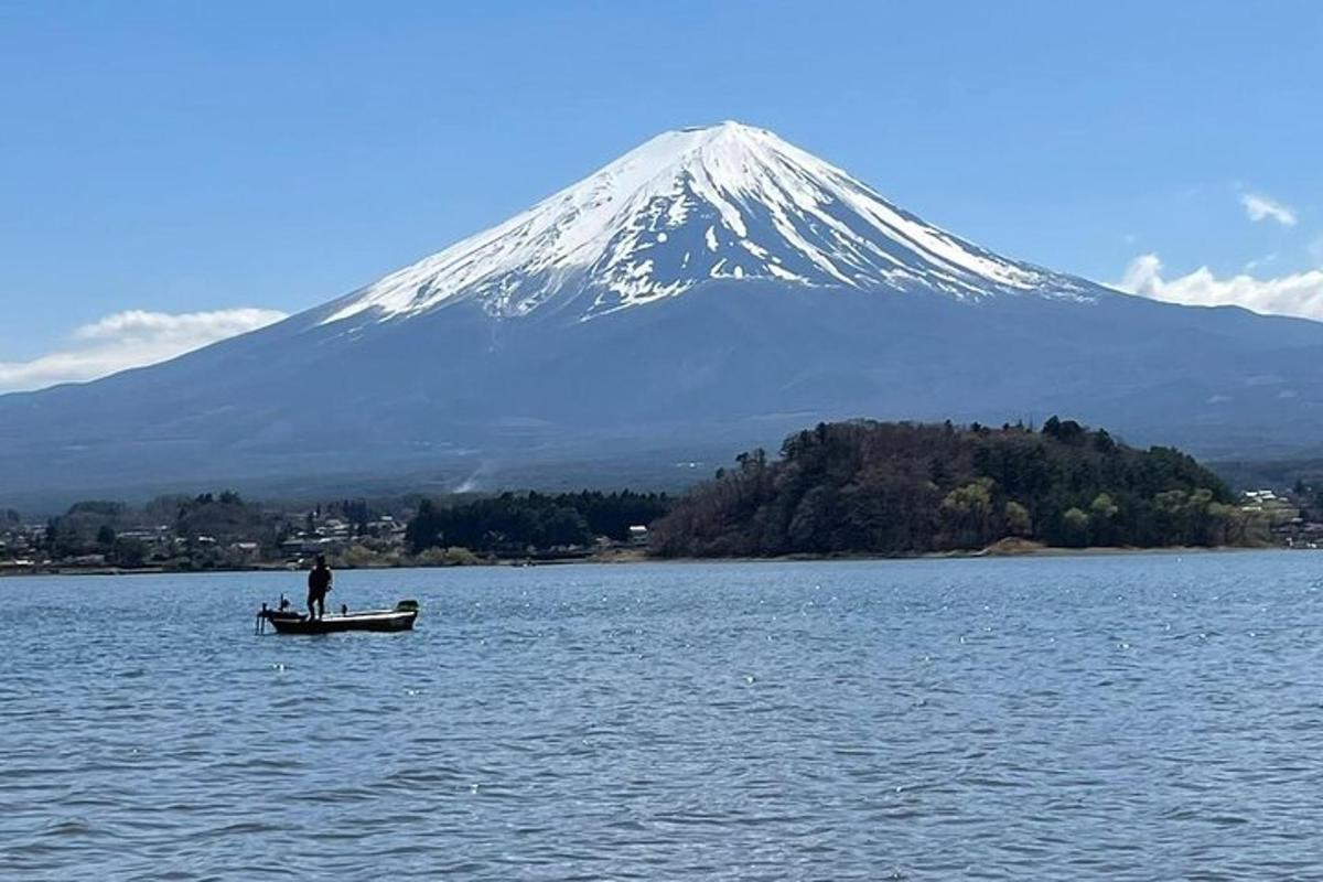 Un hombre en un bote en el agua frente a una montaña.