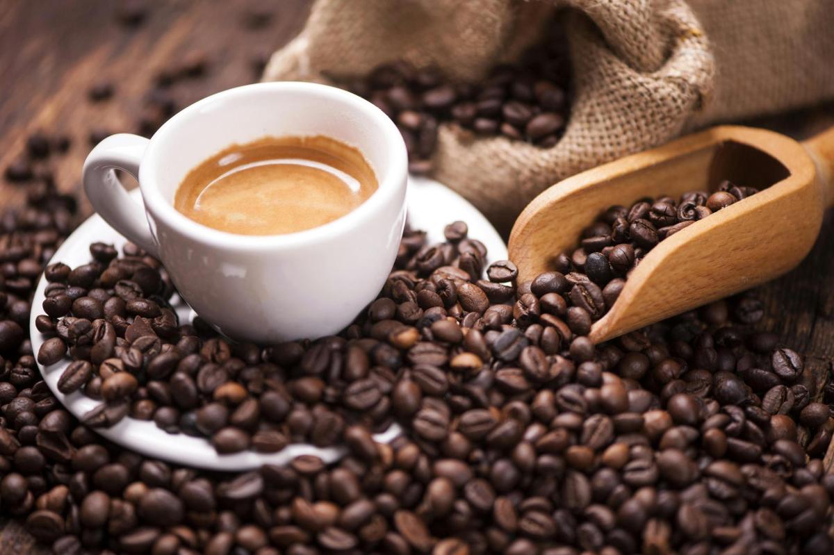 una tazza di caffè appoggiata su una pila di chicchi di caffè