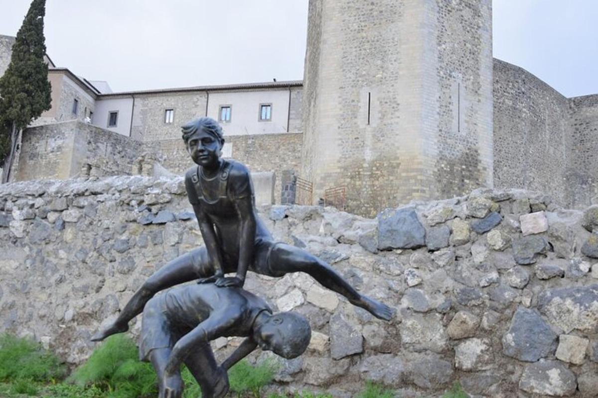 a statue of two people jumping over a rock in front of a building