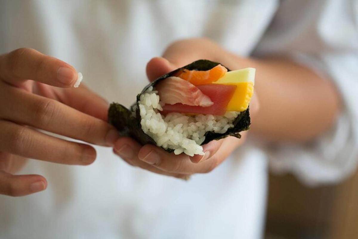 una persona che tiene in mano un panino con sushi e verdure