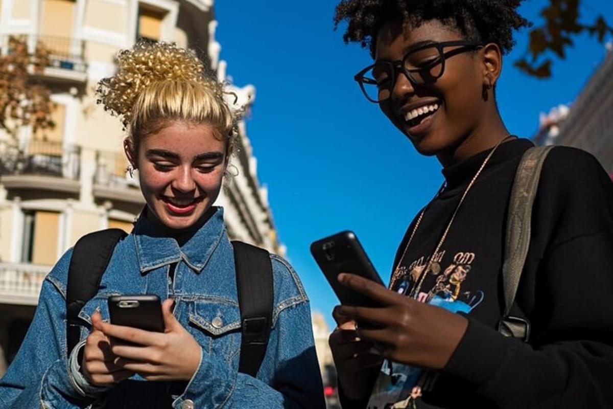 due donne che ridono mentre guardano i loro cellulari