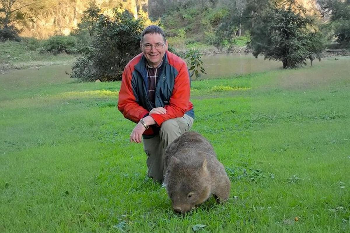 un uomo inginocchiato accanto a un maiale in un campo