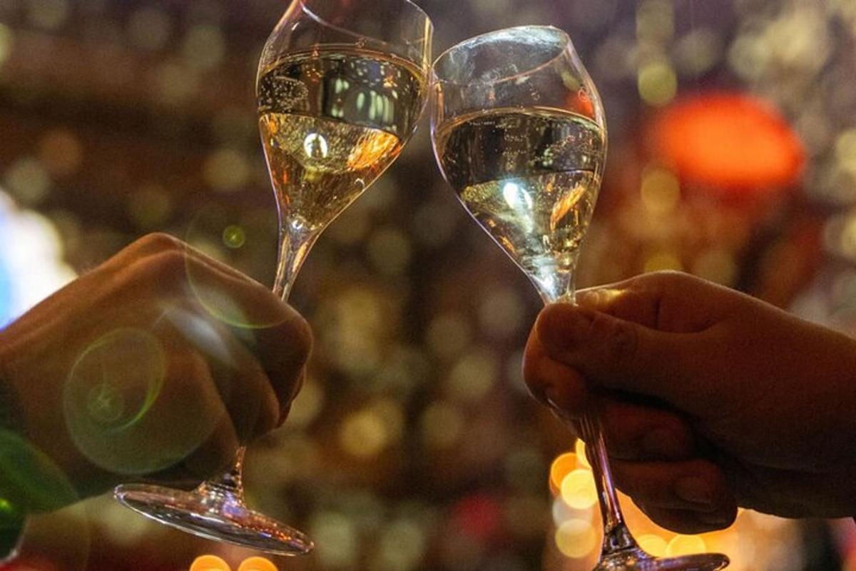 dwie osoby trzymające kieliszki z białym winem