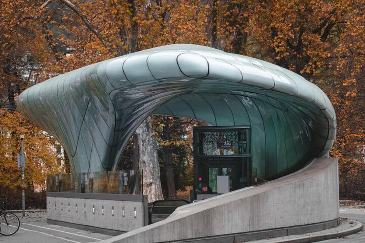 a green building with a curved roof in a park