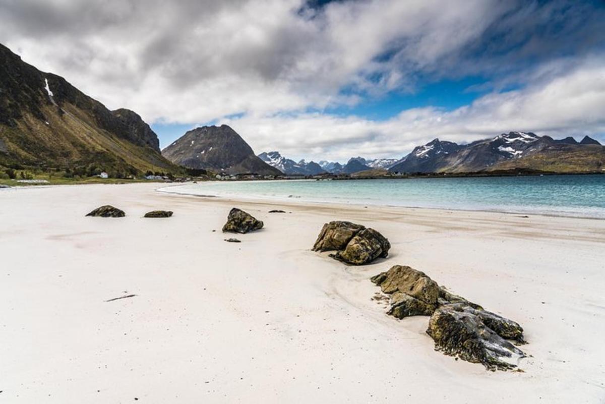a beach with rocks in the sand and mountains
