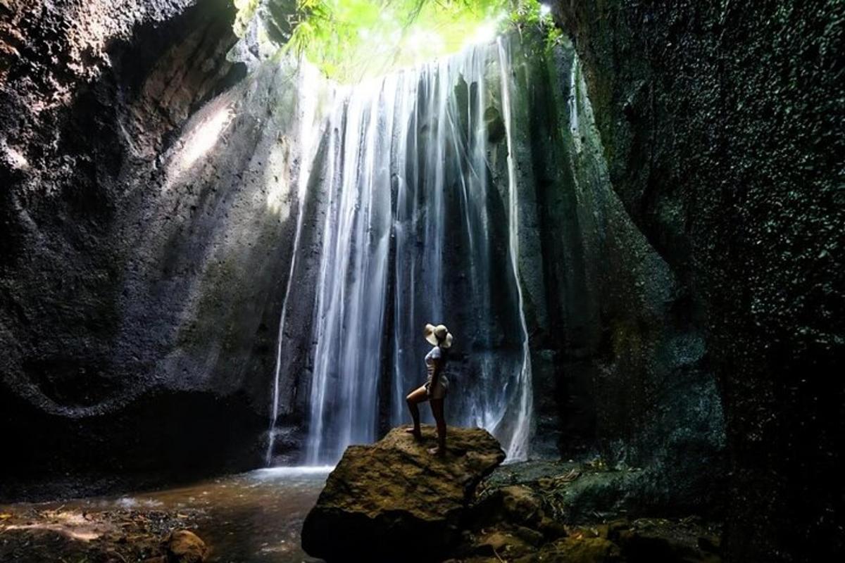seorang wanita berdiri di atas batu di hadapan air terjun