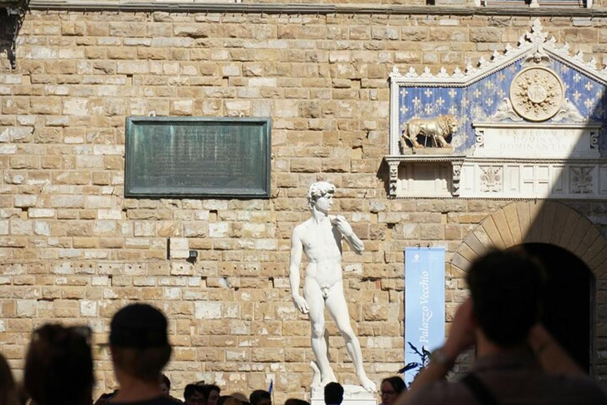 une statue d'un homme debout à côté d'un mur de briques