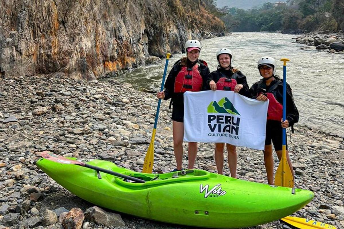 três pessoas em pé ao lado de um caiaque verde em um rio