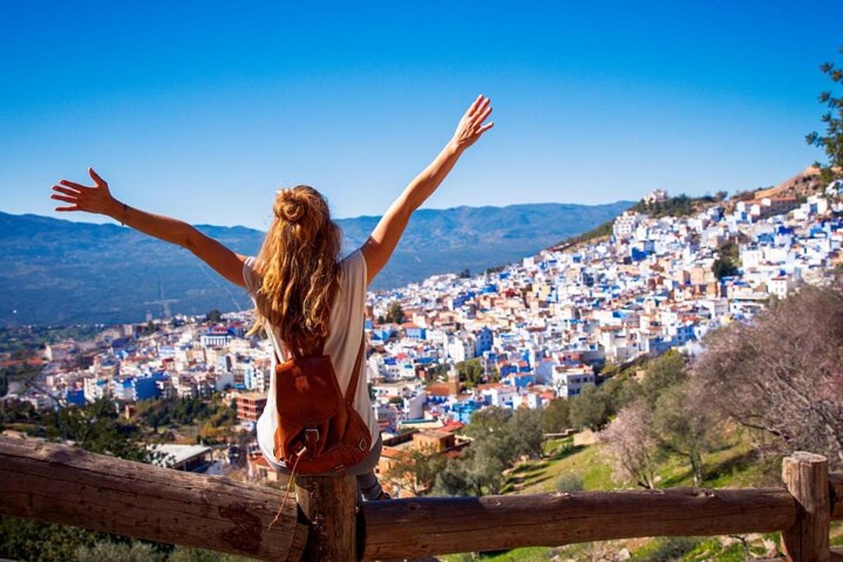 a woman standing on a fence looking at a city