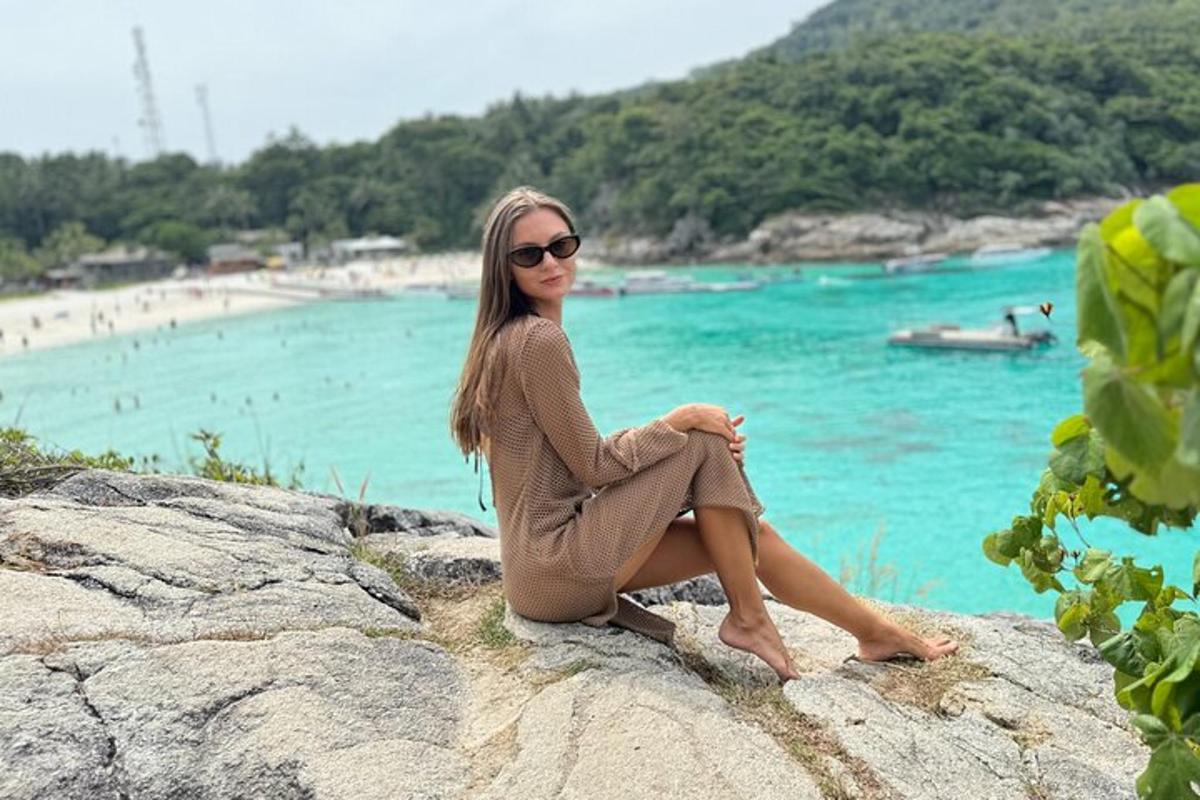 una donna seduta su una roccia vicino a una spiaggia