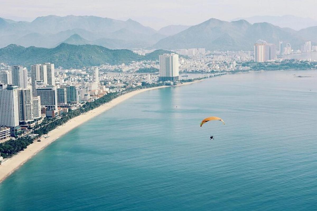una persona fent volar un estel sobre l'aigua al costat d'una platja