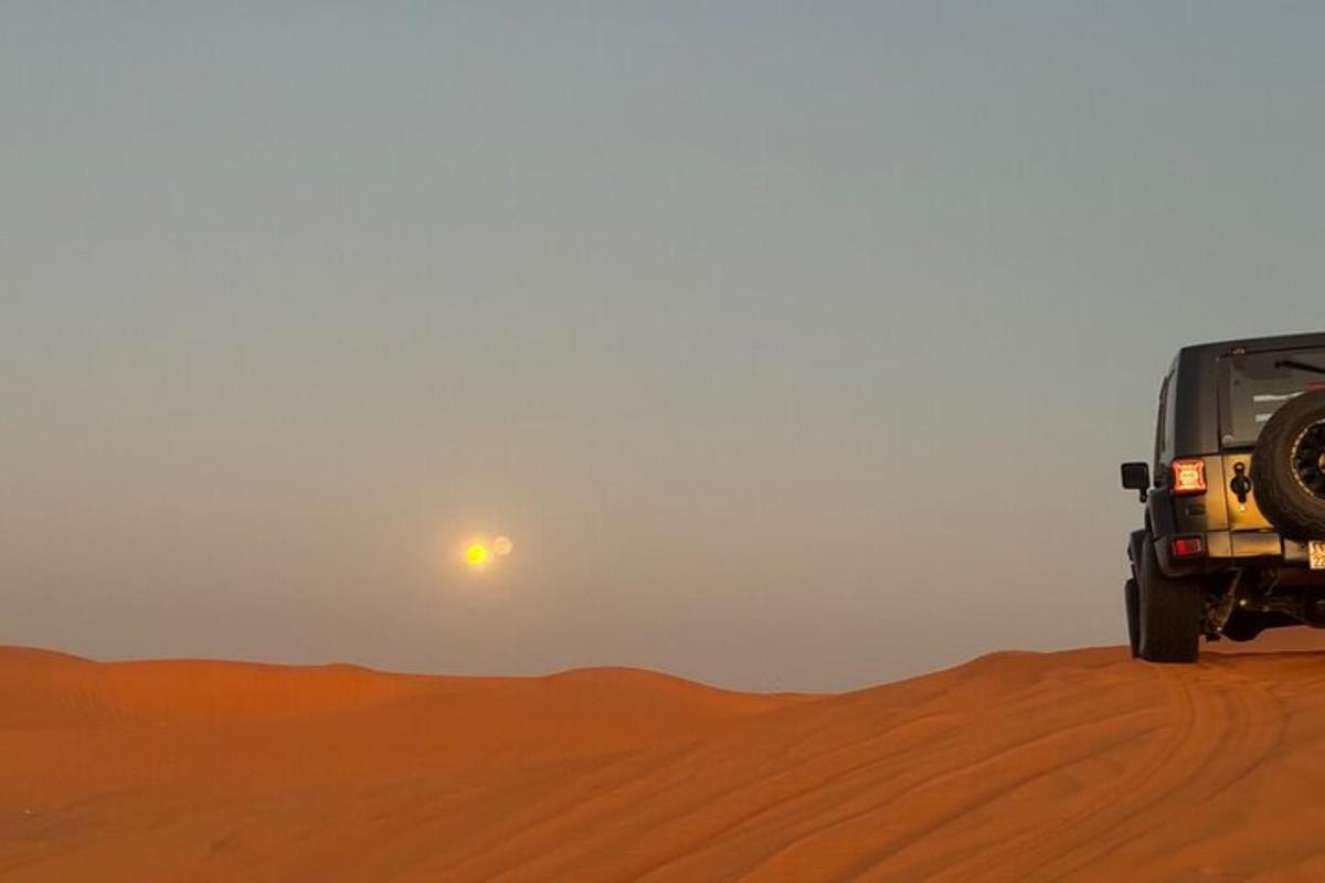 um jipe no deserto com o sol ao fundo
